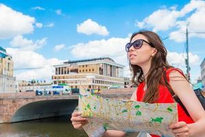 Happy young woman with a city map in Europe. Travel tourist woman with map outdoors during holidays in Europe. photo