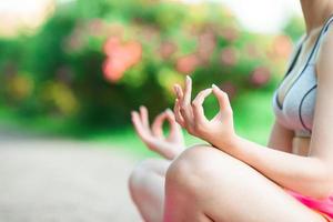 Fitness young woman meditating in the park. Female fitness model training outside in the park. Healthy wellness fitness lifestyle. photo