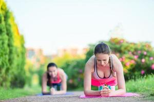 Sport fitness women training push-ups. Female athlete exercising push up outside in empty park. Fit girl fitness model in crossfit exercise outdoors. Healthy lifestyle concept. photo