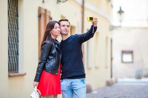 Young couple traveling on holidays in Europe smiling happy. Caucasian family making selfie in european empty old streets photo