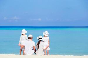 Back view of a happy family in white on the beach photo