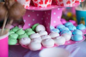 Sweet colored meringues, popcorn, custard cakes and cake pops on table photo