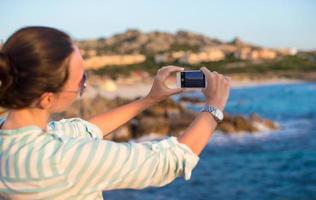 mujer joven toma una foto por teléfono durante las vacaciones en la playa