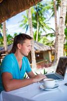 Young businessman using laptop during summer tropical vacation photo