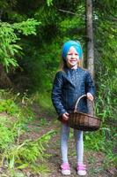 Little girl gathering mushrooms in autumn forest photo