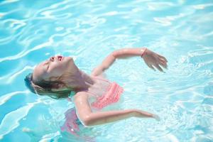 Happy little girl having fun in outdoor swimming pool photo