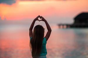 Silhouette of heart made by kids hand at sunset photo