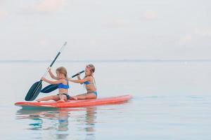 niñas lindas nadando en tablas de surf durante las vacaciones de verano foto