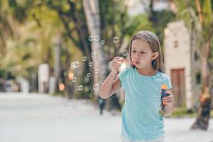 Adorable little girl making soap bubbles during summer vacation photo