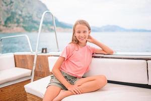 Little girl sailing on boat in clear open sea photo