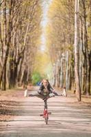 Adorable girl riding a bike at beautiful autumn day outdoors photo