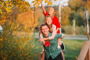 Family of dad and kids on beautiful autumn day in the park photo