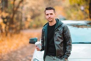 joven bebiendo café con teléfono en el parque de otoño al aire libre foto