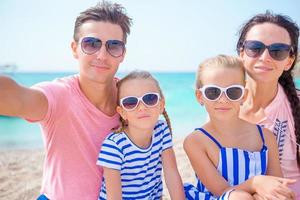 joven y hermosa familia tomando selfie en la playa foto