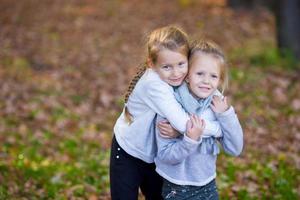 Little adorable sisters at warm sunny autumn day outdoors photo