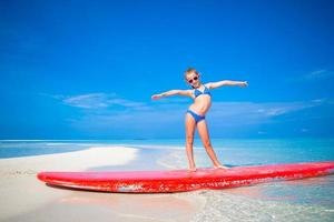 Little girl have fun on surfboard at tropical beach photo