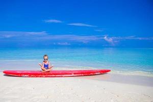 Little girl have fun on surfboard at tropical beach photo