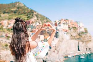 Happy girl making with hands heart shape on the old coastal village in Cinque Terre National Park. photo