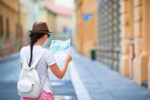 Happy young woman with a city map in city. Travel tourist woman with map in Prague outdoors during holidays in Europe. photo