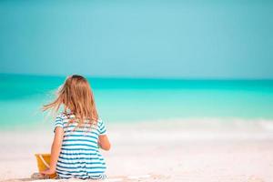 niña en la playa blanca tropical haciendo castillos de arena foto