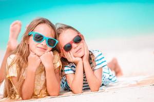 Little happy funny girls have a lot of fun at tropical beach playing together. Sunny day with rain in the sea photo