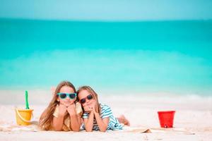 Little happy funny girls have a lot of fun at tropical beach playing together. Sunny day with rain in the sea photo