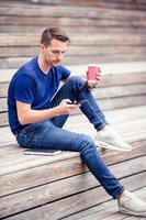 Man is reading text message on mobile phone while walking in the park photo