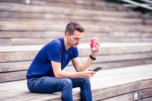 Man is reading text message on mobile phone while walking in the park photo