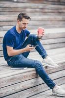 Man is reading text message on mobile phone while walking in the park photo