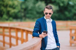 Man is reading text message on mobile phone while walking in the park photo