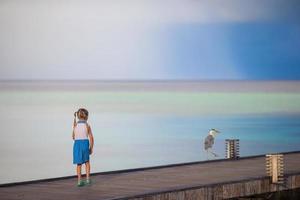 Adorable happy little girl with Grey heron on beach vacation photo