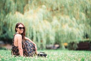 Cute woman is reading text message on mobile phone while sitting in the park. photo