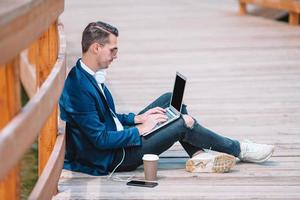 feliz joven urbano trabajando y bebiendo café en la ciudad europea al aire libre foto