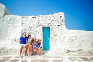 Parents and kids at street of typical greek traditional village on Mykonos Island, in Greece photo