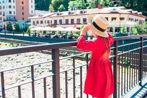 niña con sombrero en el terraplén de un río de montaña en una ciudad europea. foto