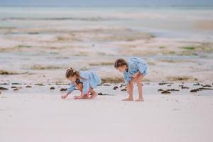 Two little happy girls have a lot of fun at tropical beach playing together photo