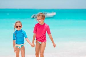 Little girls having fun at tropical beach playing together at shallow water photo