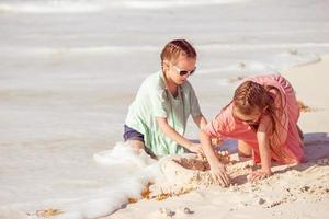 Two little happy girls have a lot of fun at tropical beach playing together photo