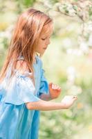 Adorable little girl in blooming apple garden on beautiful spring day photo