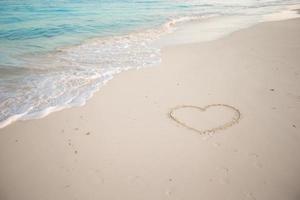 Heart painted in white sand on a tropical beach photo