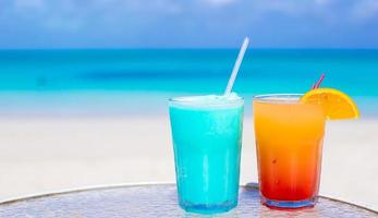 Close up Blue Curacao and Mango cocktail on the white sandy beach photo