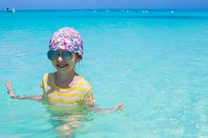 Adorable little girl in the sea on tropical beach vacation photo