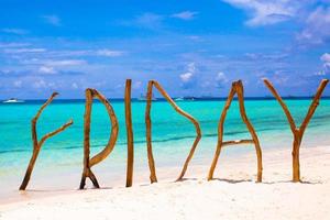 Perfect white sandy beach and turquoise sea on tropical island with wooden letters made Friday word photo