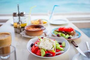Traditional lunch with delicious fresh greek salad, frappe and brusketa served for lunch at outdoor cafe photo