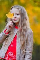 adorable niña al aire libre en un hermoso día cálido en el parque de otoño con hojas amarillas en otoño foto