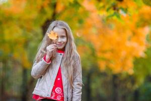 increíble niña al aire libre en un hermoso día cálido en el parque de otoño con hojas amarillas en otoño foto