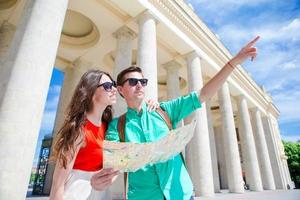 Romantic couple together with city map outdoors. Happy lovers enjoying cityscape with famous landmarks. photo