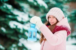 Winter day. Woman holding Christmas lantern outdoors on beautiful winter snow day photo