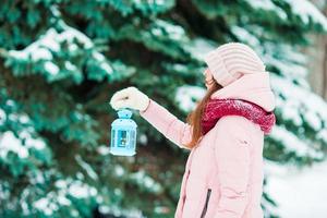 día de invierno. mujer sosteniendo linterna de navidad al aire libre en un hermoso día de nieve de invierno foto