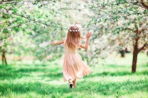 Adorable little girl in blooming cherry tree garden outdoors photo
